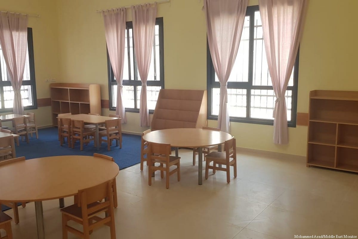 A sunlit classroom with child-sized wooden tables and chairs