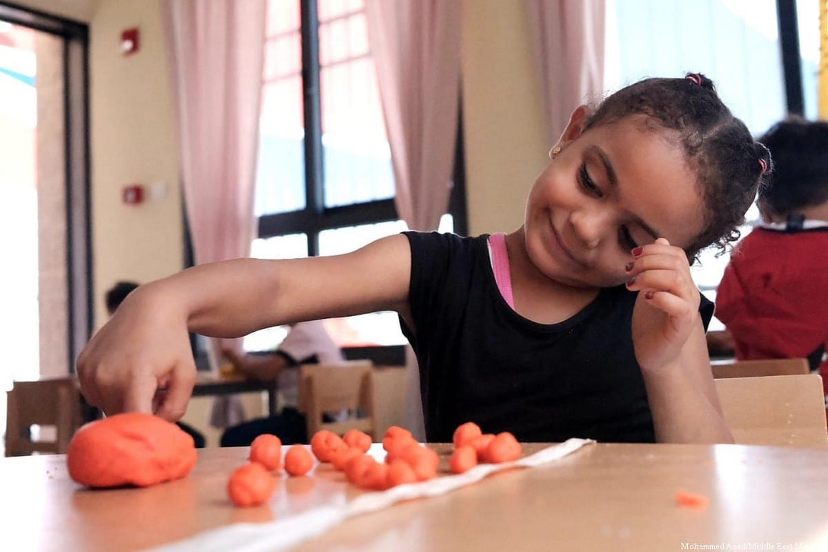 A young girl shaping play dough at her classroom table